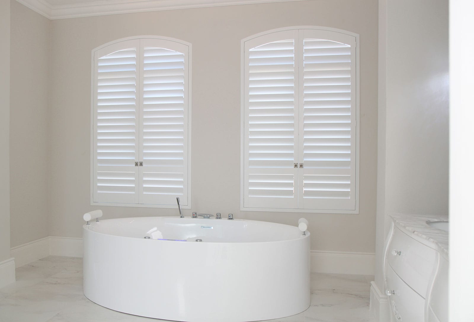 Arched white shutters in a bedroom.