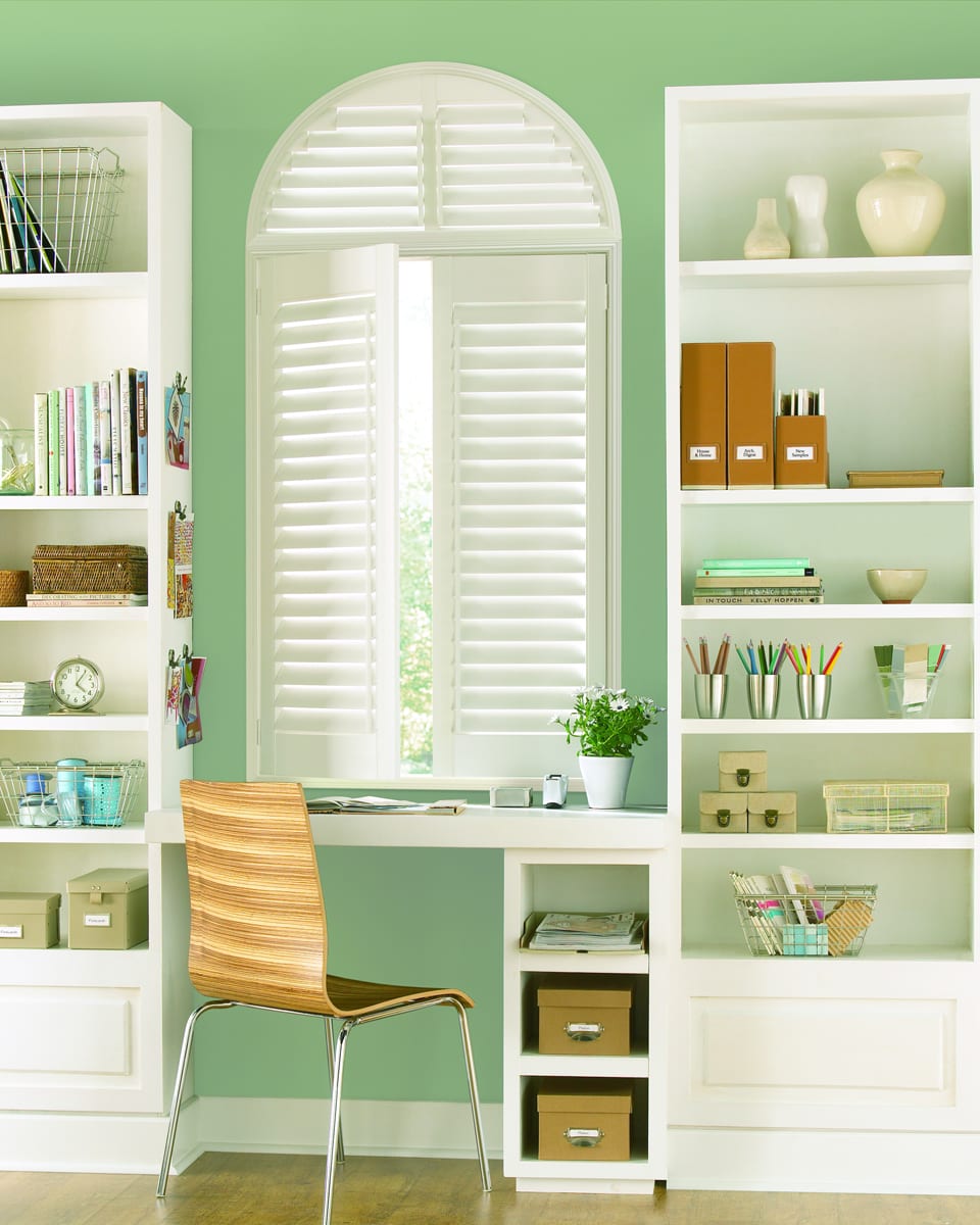 Arched window covered with white shutters.