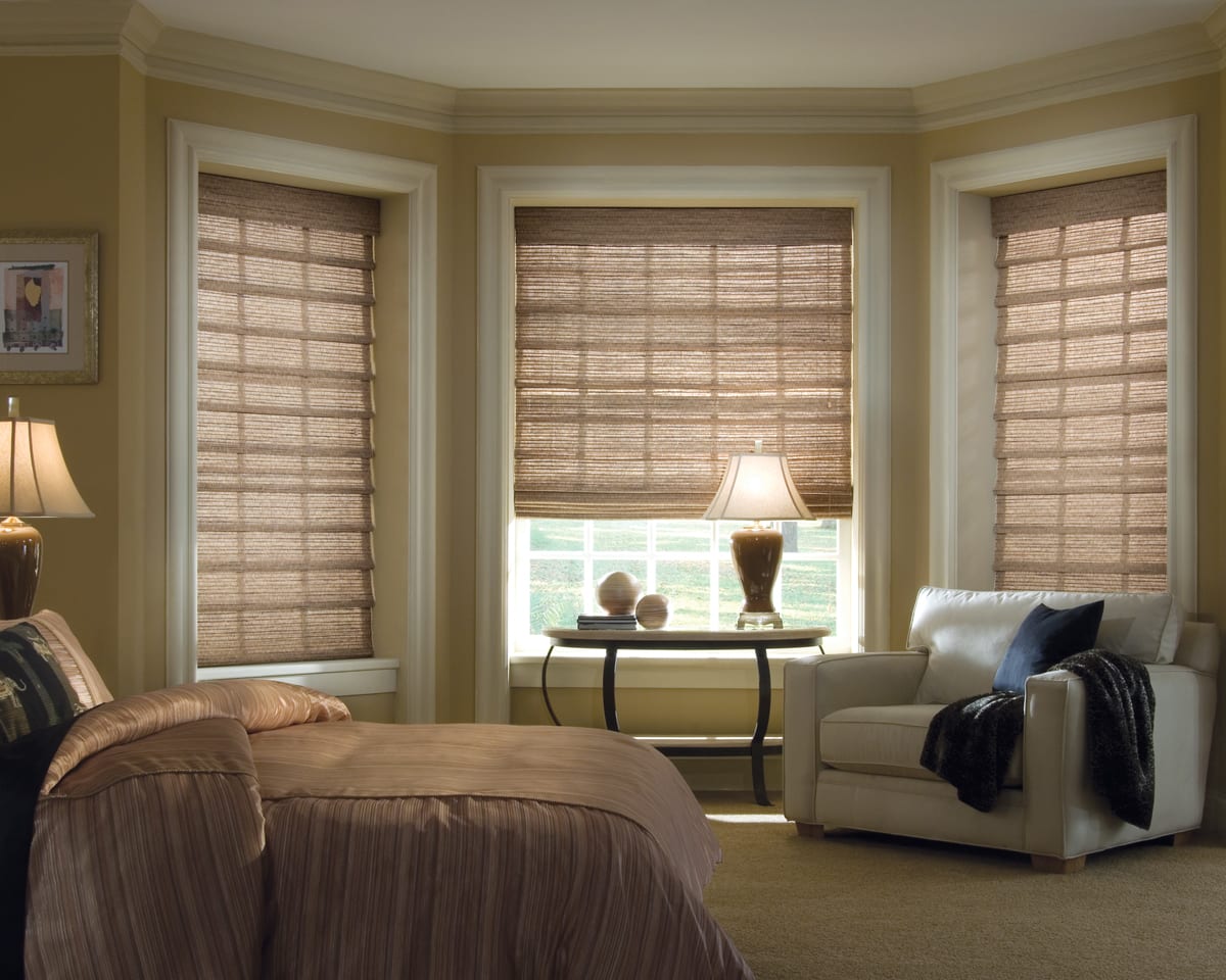 Light brown woven wood shades in a bedroom.
